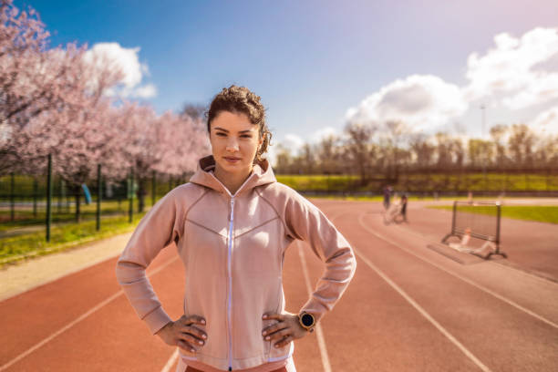 joven atleta femenina de pie en pista deportiva. - running track women running spring fotografías e imágenes de stock