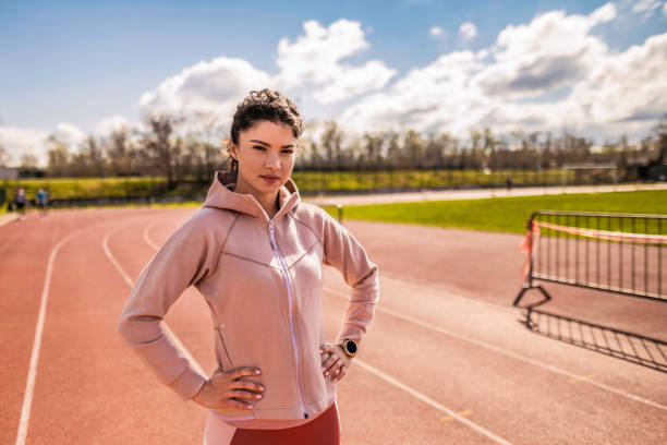 joven atleta femenina de pie en pista deportiva. - running track women running spring fotografías e imágenes de stock