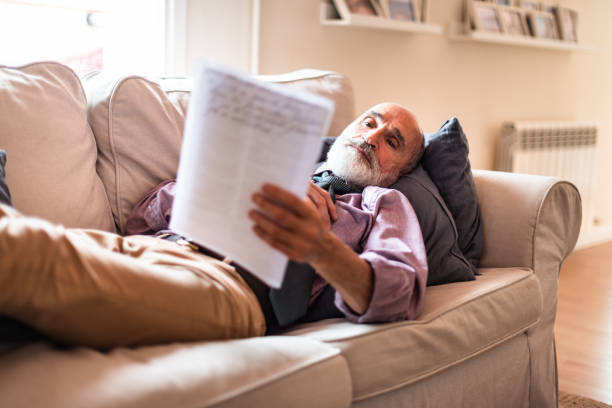 istock mature adult man reading notes on the sofa 1309155772