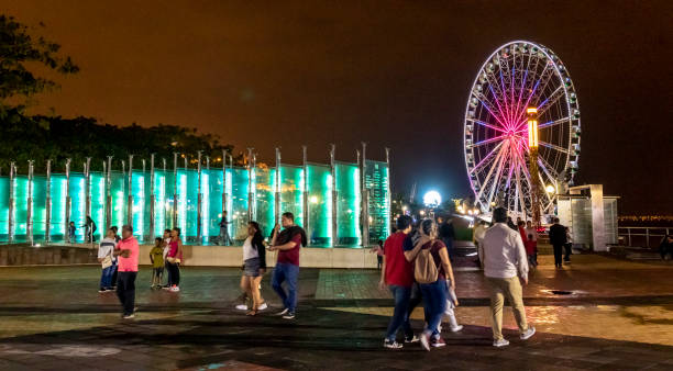 Families enjoying the Guayaquil's Malecon 2000, along the Guayas River, in the city downtown. Visible in the foreground is the Donors’ Pavilion memorial and the Ferris Wheel in the background