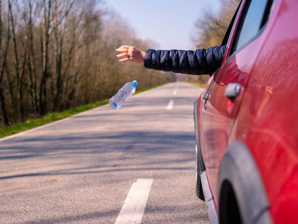istock Driver throwing away plastic waste from car window on the road 1309160860