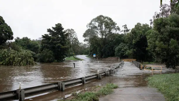 Photo of Queensland Australia 23 March 2021 Flooded Road after torrential rain and dam overflowing. River overflowing onto Youngs Crossing and over the pedestrian walkway.