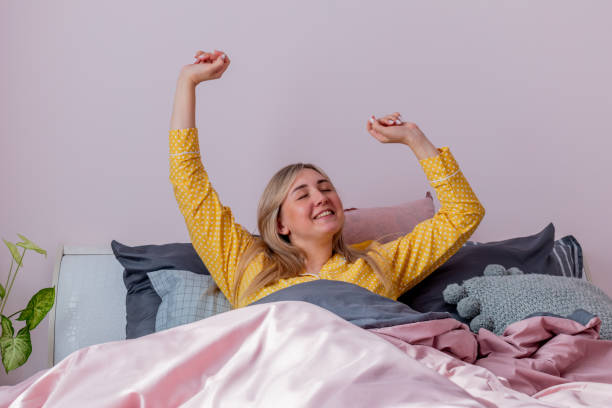 istock Young woman yawns stretches while sitting in comfortable soft bed. 1309164950