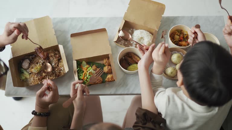 Top view asian chinese young family enjoying take out food in front of tv in living room during weekend