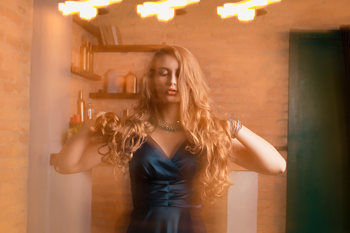 Fabulous blonde lady in dress posing in mixed  light at studio