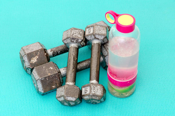 istock Old gym dumbbells or exercise weights and a bottle 1309167332