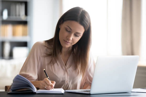 istock Close up confident woman writing notes, sitting at work desk 1309167649