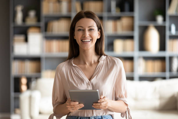 Head shot portrait smiling woman holding computer tablet in hands