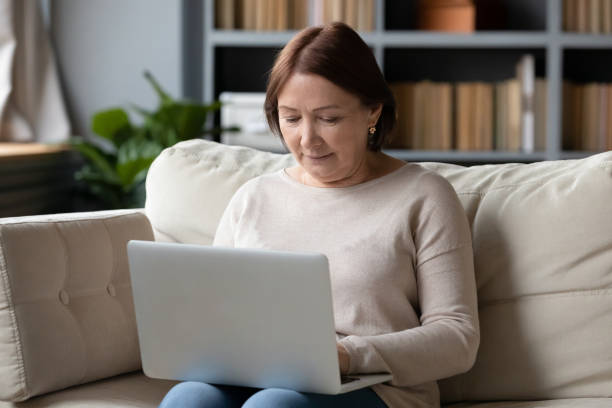 istock Close up mature woman using laptop, sitting on couch 1309167692