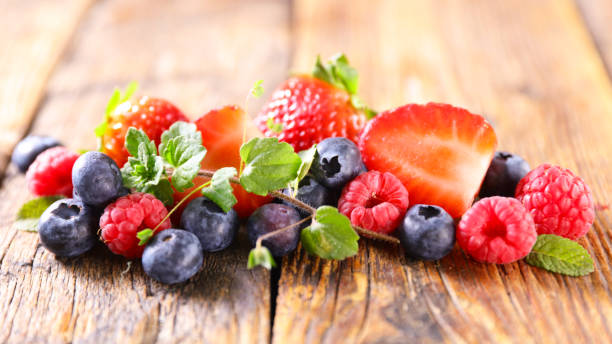 istock berries fruits and mint on wood background 1309167796