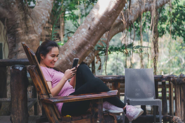 istock Happy asian woman using mobile phone in a comfortable sitting position while sitting in a coffee shop. 1309171569