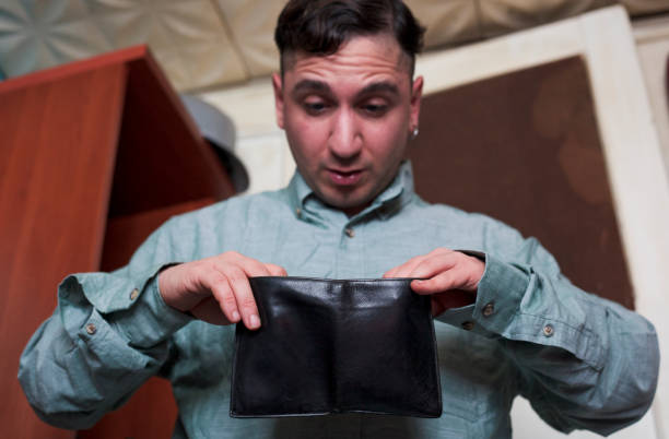 istock young man looking at his wallet in astonishment 1309171604