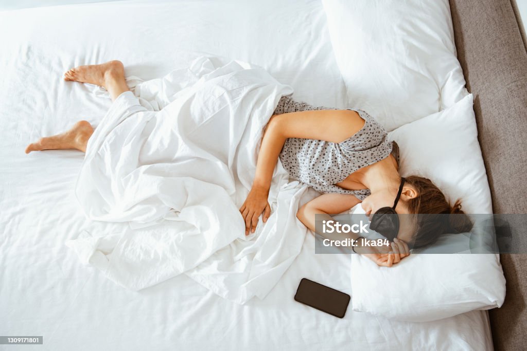 It's time to wake up A young woman sleeping in bed. Time to sleep and rest. A woman lying in bed at home, it's time to wake up. Adult Stock Photo