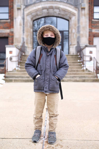 istock Third Grade Boy Child in Covid Face Mask Outside Elementary School Education Building 1309198927