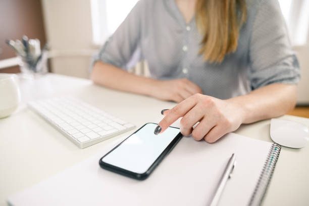istock cropped shot of a young woman working from home using smart phone and computer, woman's hands using smart phone in interior, woman at home workplace using technology, selective focus 1309202994