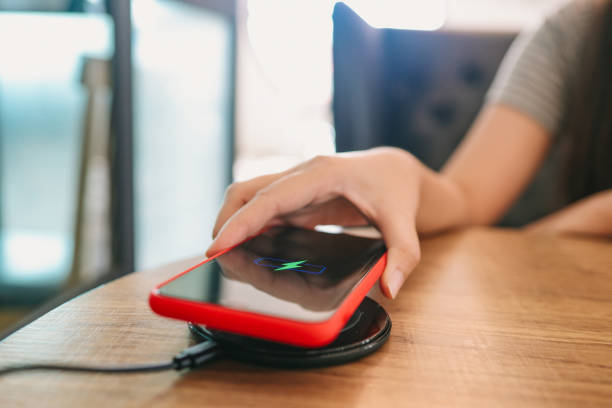 istock Charging mobile phone battery with wireless charging device in the table. Smartphone charging on a charging pad. Mobile phone near wireless charger Modern lifestyle concept. 1309204042