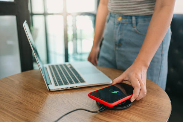 Charging mobile phone battery with wireless charging device in the table. Smartphone charging on a charging pad. Mobile phone near wireless charger Modern lifestyle concept.