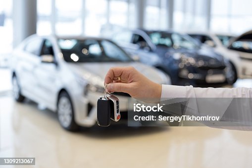 istock Salesman holding keys to a new car. Car auto dealership. 1309213067