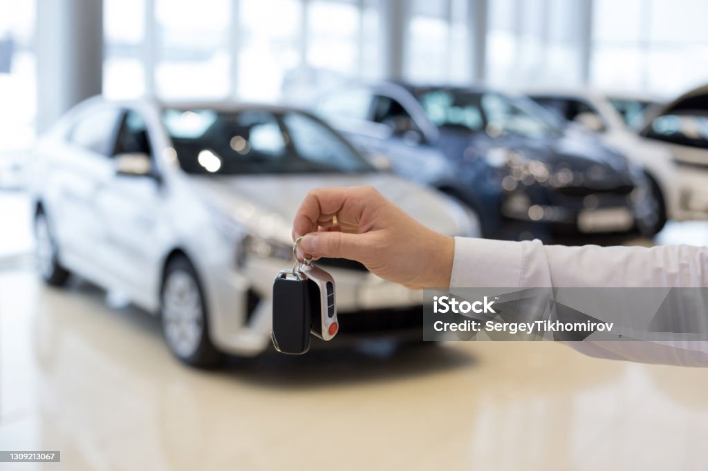 Salesman holding keys to a new car. Car auto dealership. Salesman holding keys to a new car. Car auto dealership. Modern and prestigious vehicles. Car Stock Photo