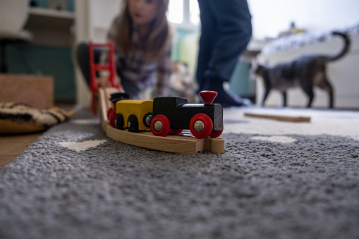 Kids playing in a room with a wooden train