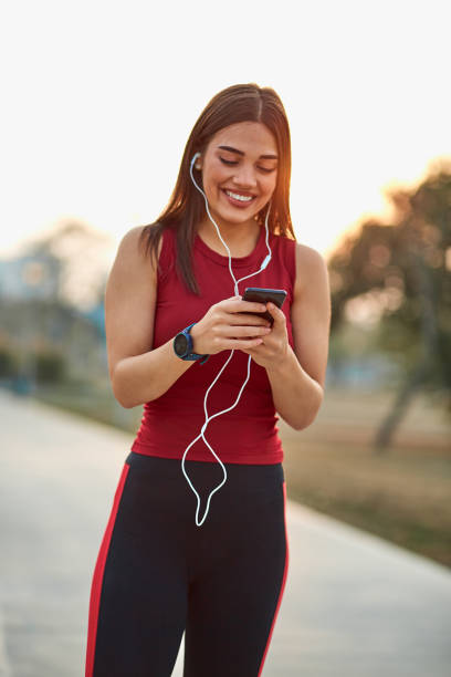 istock Modern young woman with cellphone making pause during jogging exercise. 1309217368