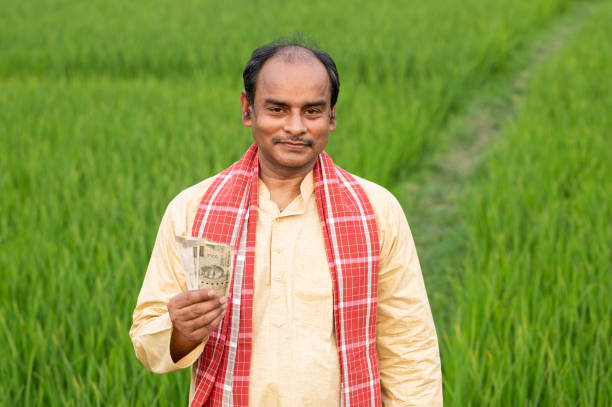 istock Farmer holding Indian Rupee notes in middle of green Crops. 1309220729