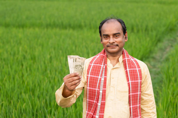 istock Farmer holding Indian Rupee notes in middle of green Crops. 1309220807