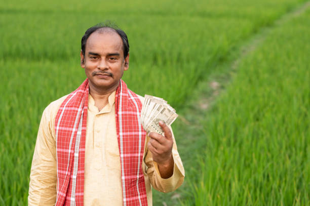 istock Farmer holding Indian Rupee notes in middle of green Crops. 1309220937