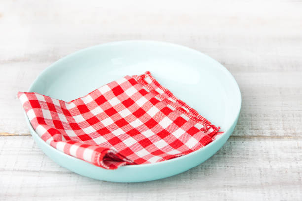 Plate with cloth napkin inside on wooden background