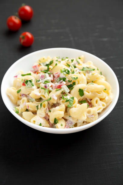 istock Homemade Macaroni Salad in a white bowl on a black surface, side view. 1309223981