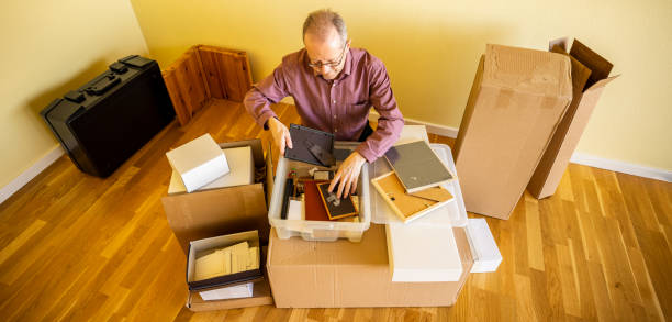 istock Looking through nostalgic stuff, a senior man in empty apartment room, unpacking from cardbox boxes for moving house 1309226305