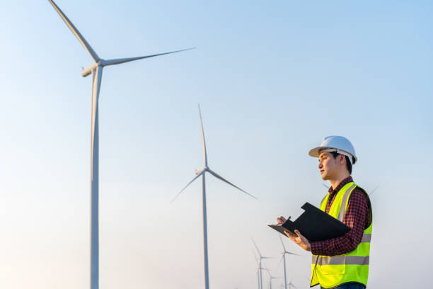 istock male engineer working and writing on clipboard against wind turbine farm 1309227589