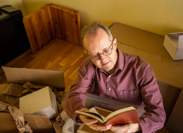 istock Reading an old diary book, a middle aged caucasian man in empty apartment room, unpacking from cardbox boxes for moving house 1309227662