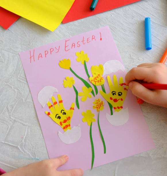 istock Child making card with Easter funny eggs and flowers  from colorful paper. 1309228018