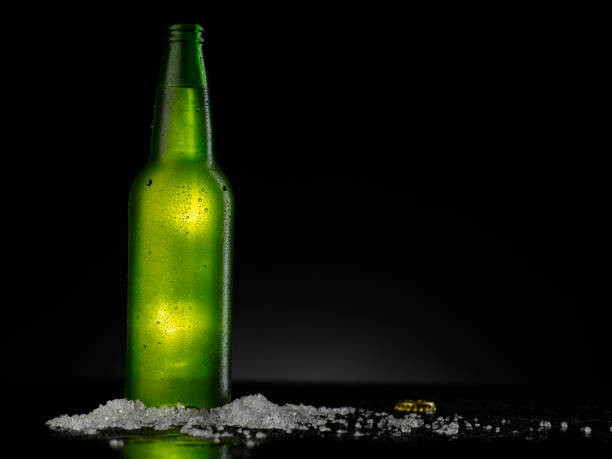 istock Ice Cold Green Beer Bottle Covered with water drops - condensation. Blank for drink beverage product design mock-up.  Standing on black table with dark - black background. 1309228104