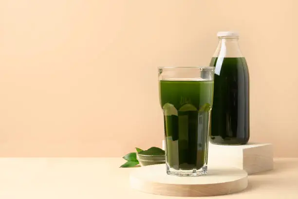 Chlorella Detox drink in glass on modern beige background. Space for text.