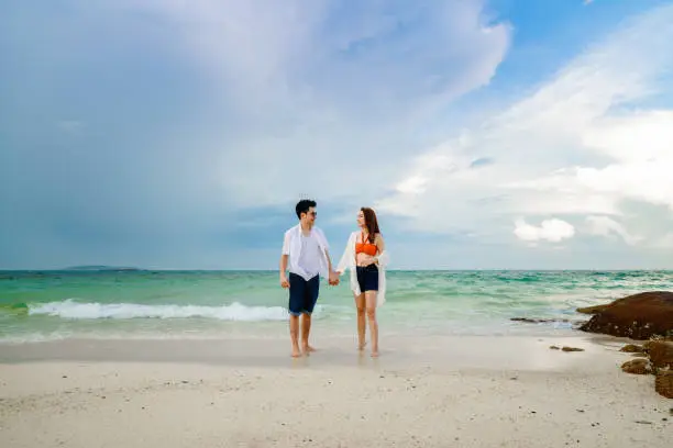 happy young couple walking on the sea beach at Koh MunNork Island, Rayong, Thailand