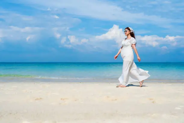 cheerful pregnant woman walking on the sea beach at Koh MunNork Island, Rayong, Thailand