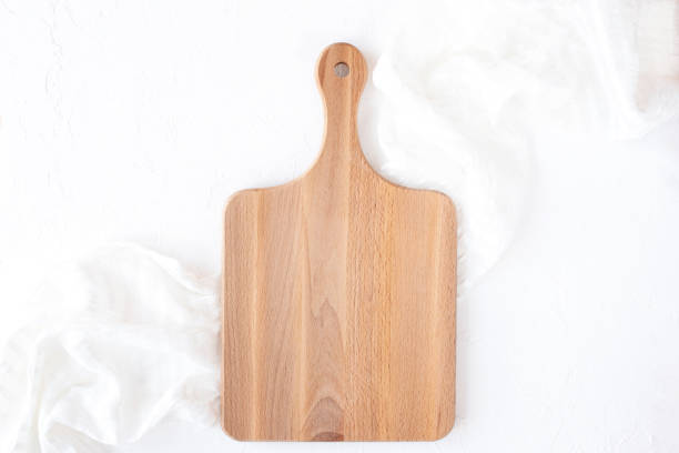 istock Wooden cutting board on white napkin and background, flat 1309231025