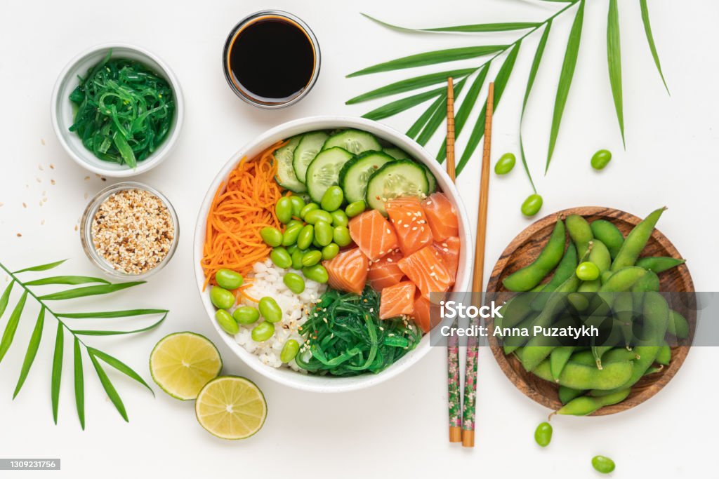 Poké bowl with raw salmon Bowl with raw fish, rice, chukka salad, edamame beans, carrots and cucumber. Bowl of healthy food on white background Poke - Food Stock Photo