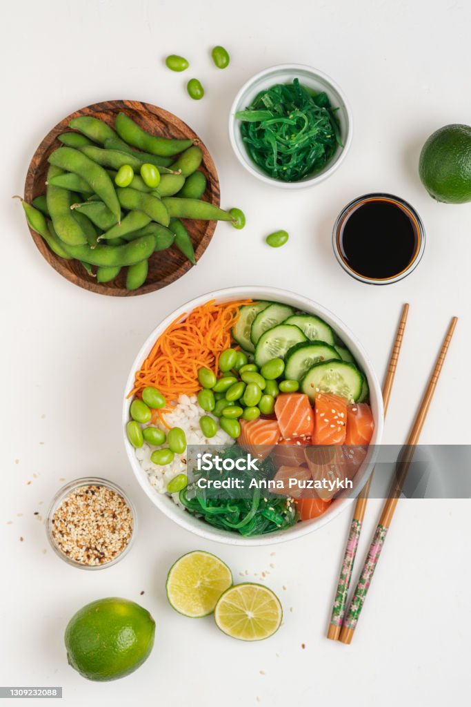 Poké bowl with raw salmon Bowl with raw fish, rice, chukka salad, edamame beans, carrots and cucumber. Bowl of healthy food on white background Above Stock Photo