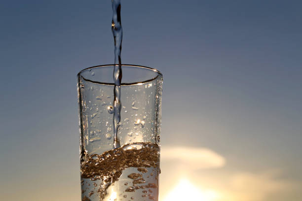 istock Clean water pouring into drinking glass on sunset blurred background 1309232229
