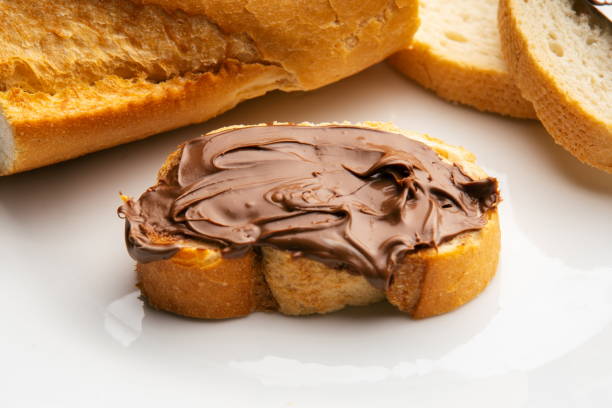 istock Bread spread with chocolates along knife and bread slices on white plate 1309234026