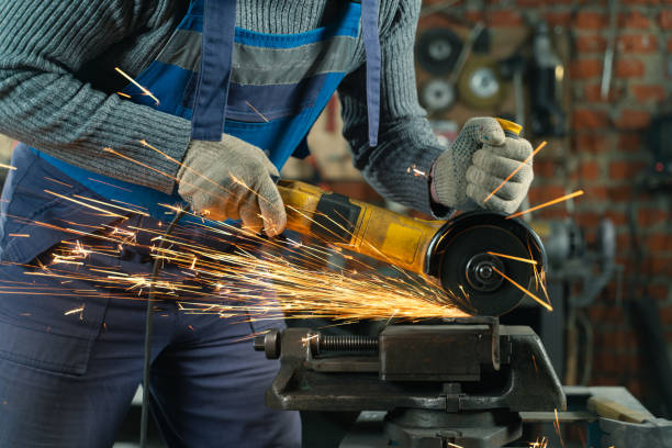 istock Locksmith in special clothes and goggles works in production. Metal processing with angle grinder. Sparks in metalworking 1309237454