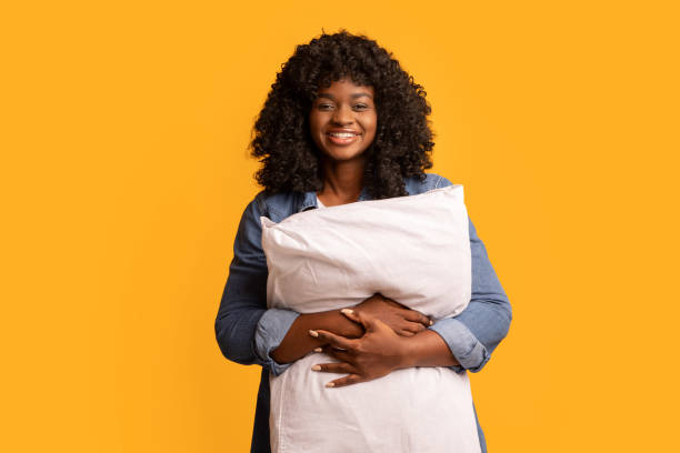 istock Happy young black woman hugging big soft pillow 1309238752
