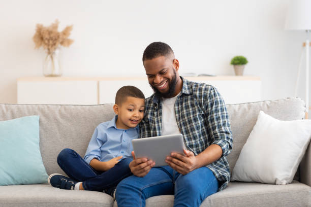istock Black Dad And Son Using Digital Tablet Sitting At Home 1309238873