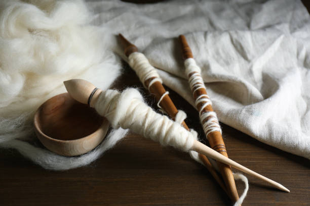 istock Spindles and soft white wool on wooden table 1309239774