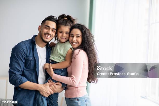 Portraif Of Happy Arabic Parents Posing With Their Little Daughter At Home Stock Photo - Download Image Now