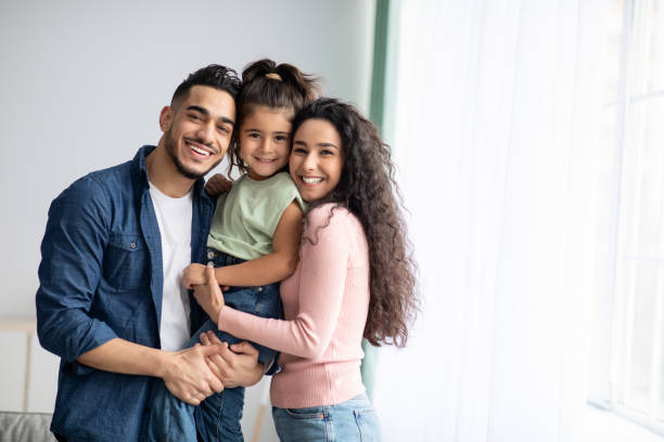 portraif of happy arabic parents posing with their little daughter at home - family portrait imagens e fotografias de stock
