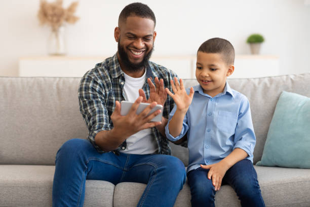istock Black Father And Son Making Video Call Using Smartphone Indoor 1309240046